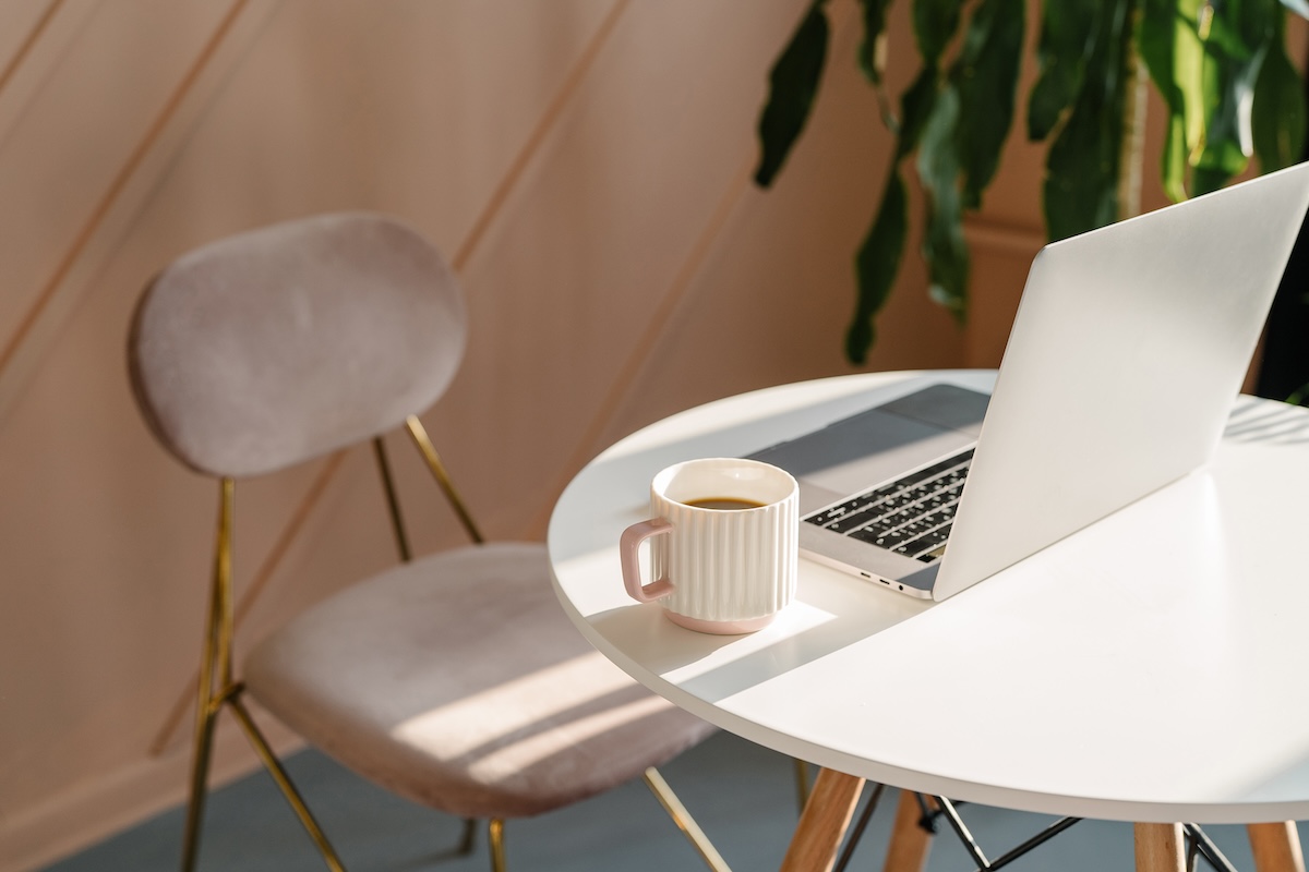 laptop and coffee on desk with pink velvet chair, Stephanie Seija Content Marketing