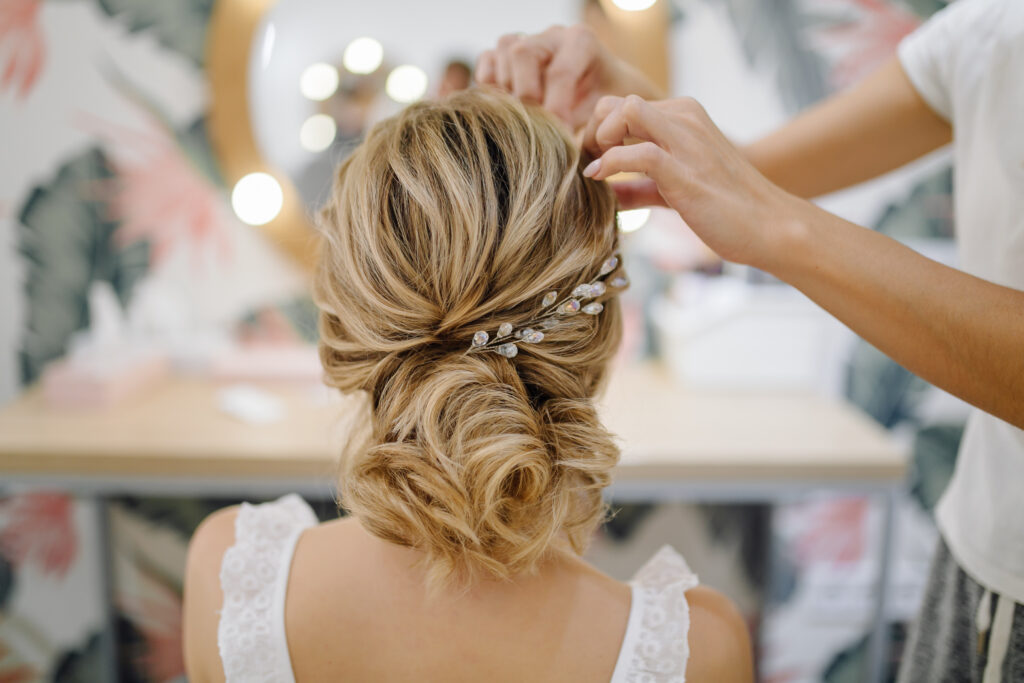back of bridal updo being tweaked by a bridal hair and makeup artist