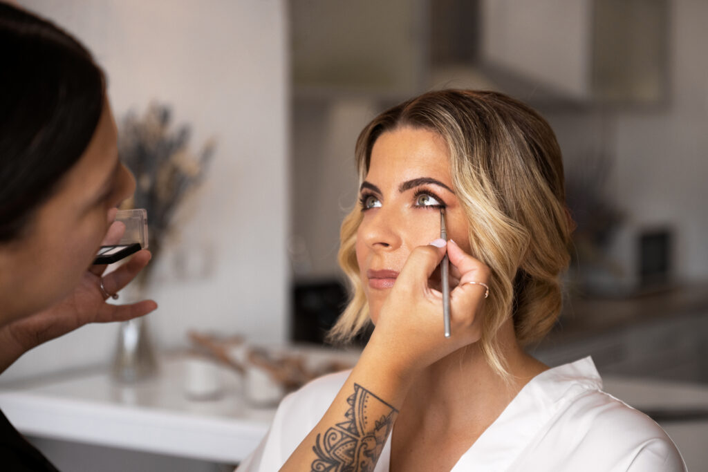 bride getting her eye makeup done by a bridal hair and makeup artist