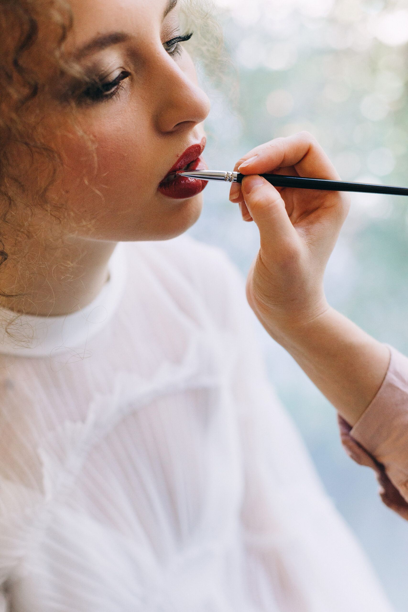 bride getting her lipstick done by a makeup artist