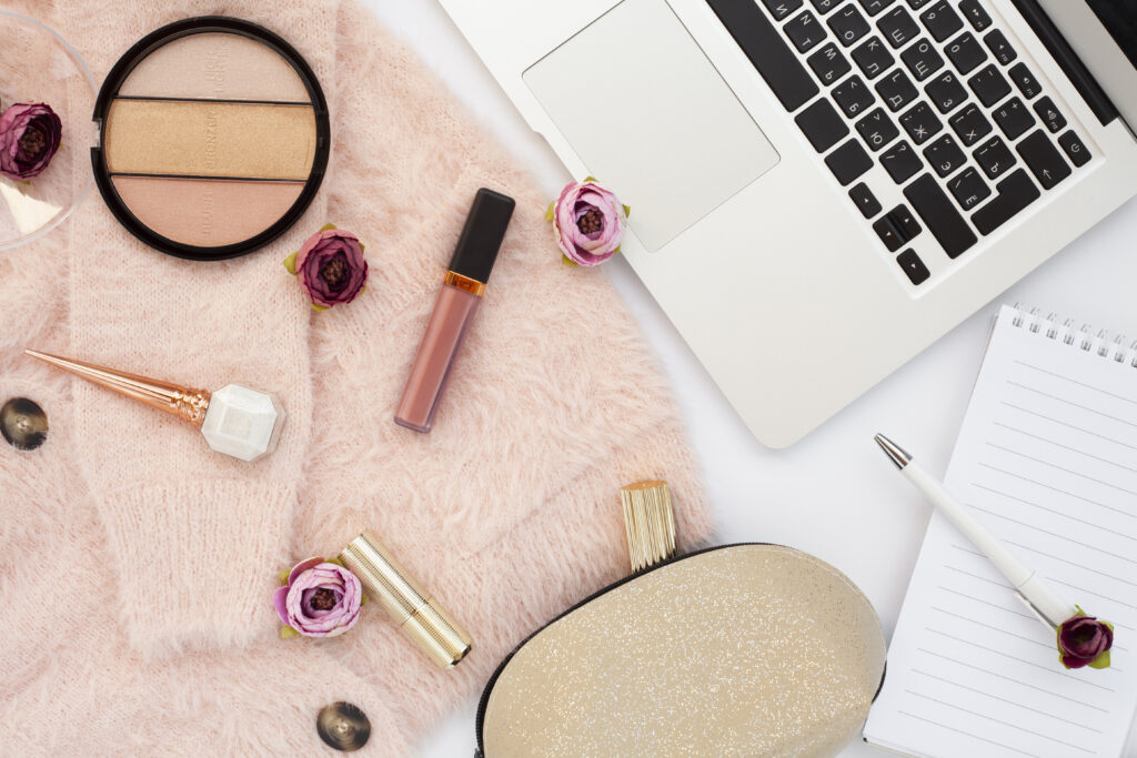laptop and makeup scattered on a desk