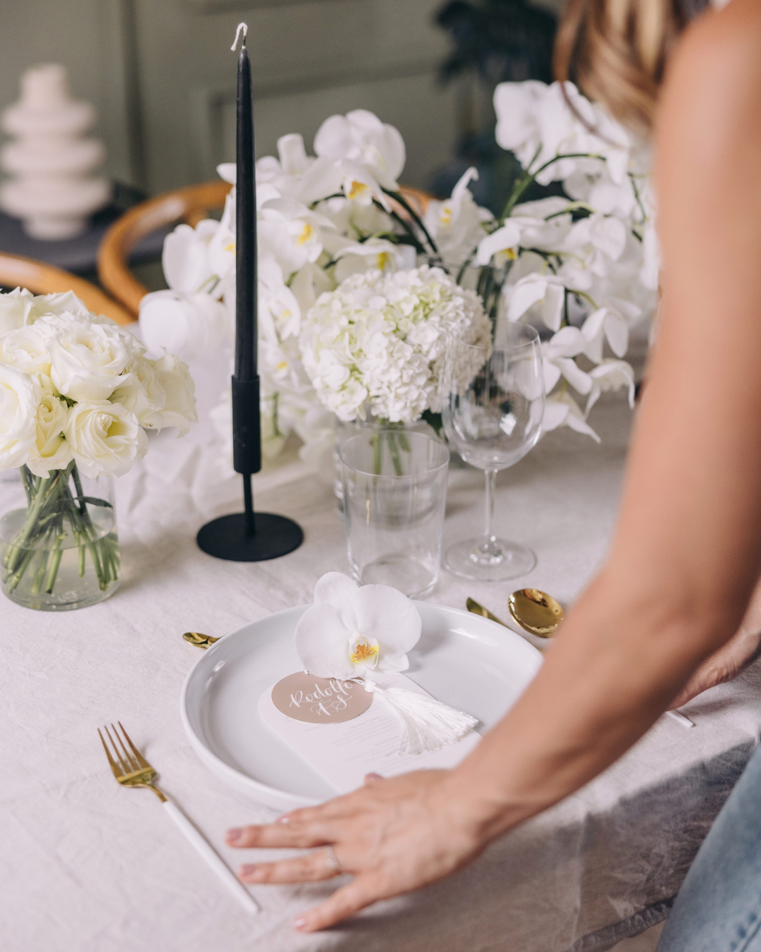wedding planner's hands adjusting a white tablescape