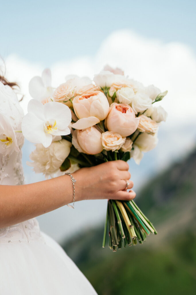 bride holding a wedding bouquet of white and peach flowers