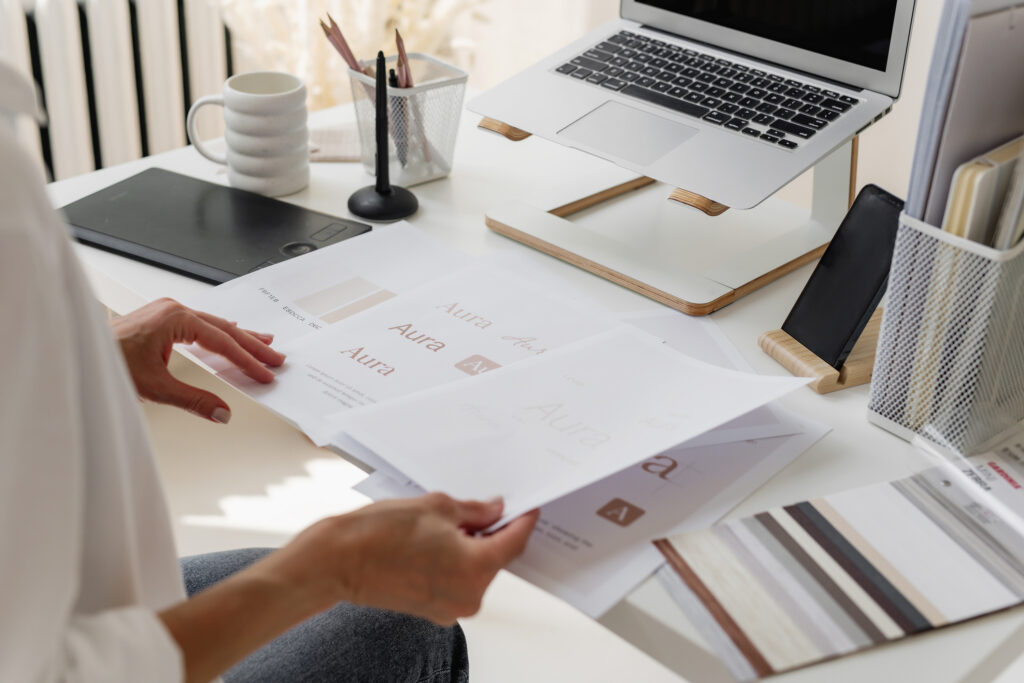 feminine hands holding papers on a desk with a laptop
