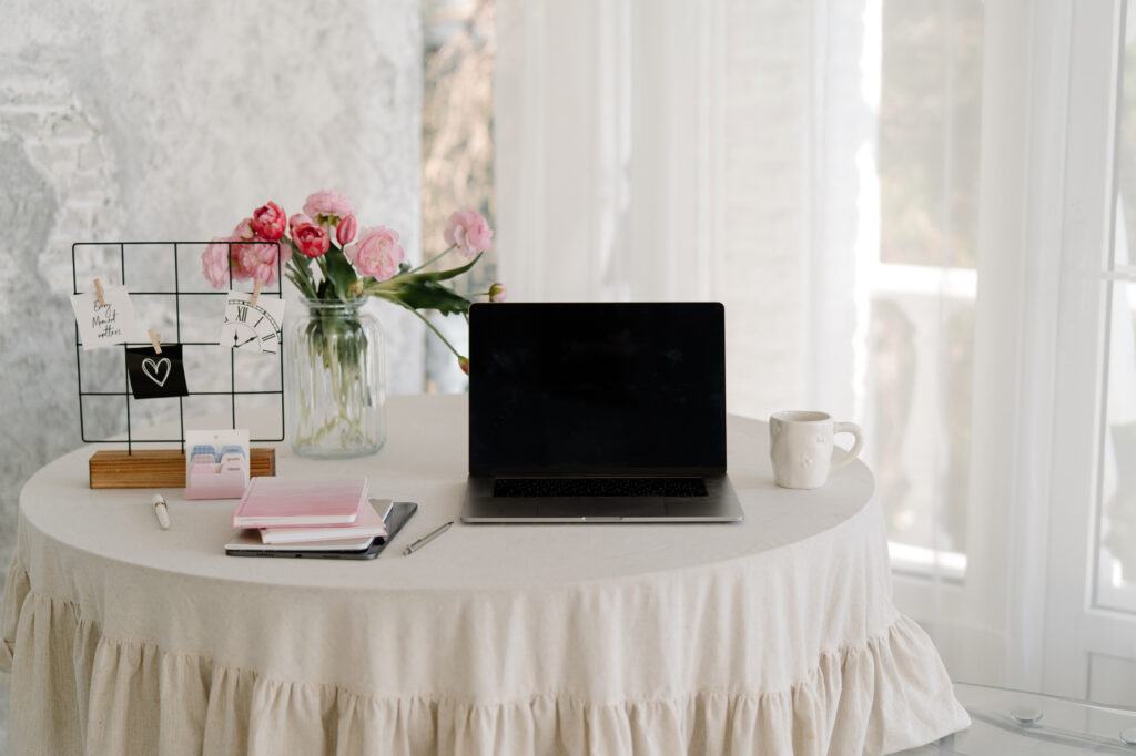 a laptop on a table with a feminine decor and pink flowers